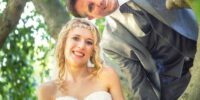 Hochzeitsfotografie - Brautpaar mit blonder Braut auf altem Baum im Grünen