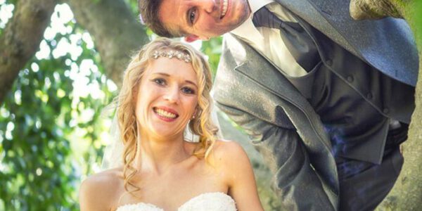 Hochzeitsfotografie - Brautpaar mit blonder Braut auf altem Baum im Grünen
