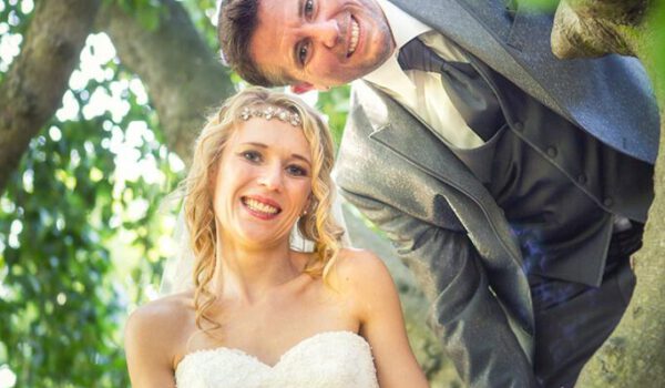 Hochzeitsfotografie - Brautpaar mit blonder Braut auf altem Baum im Grünen