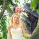 Hochzeitsfotografie - Brautpaar mit blonder Braut auf altem Baum im Grünen